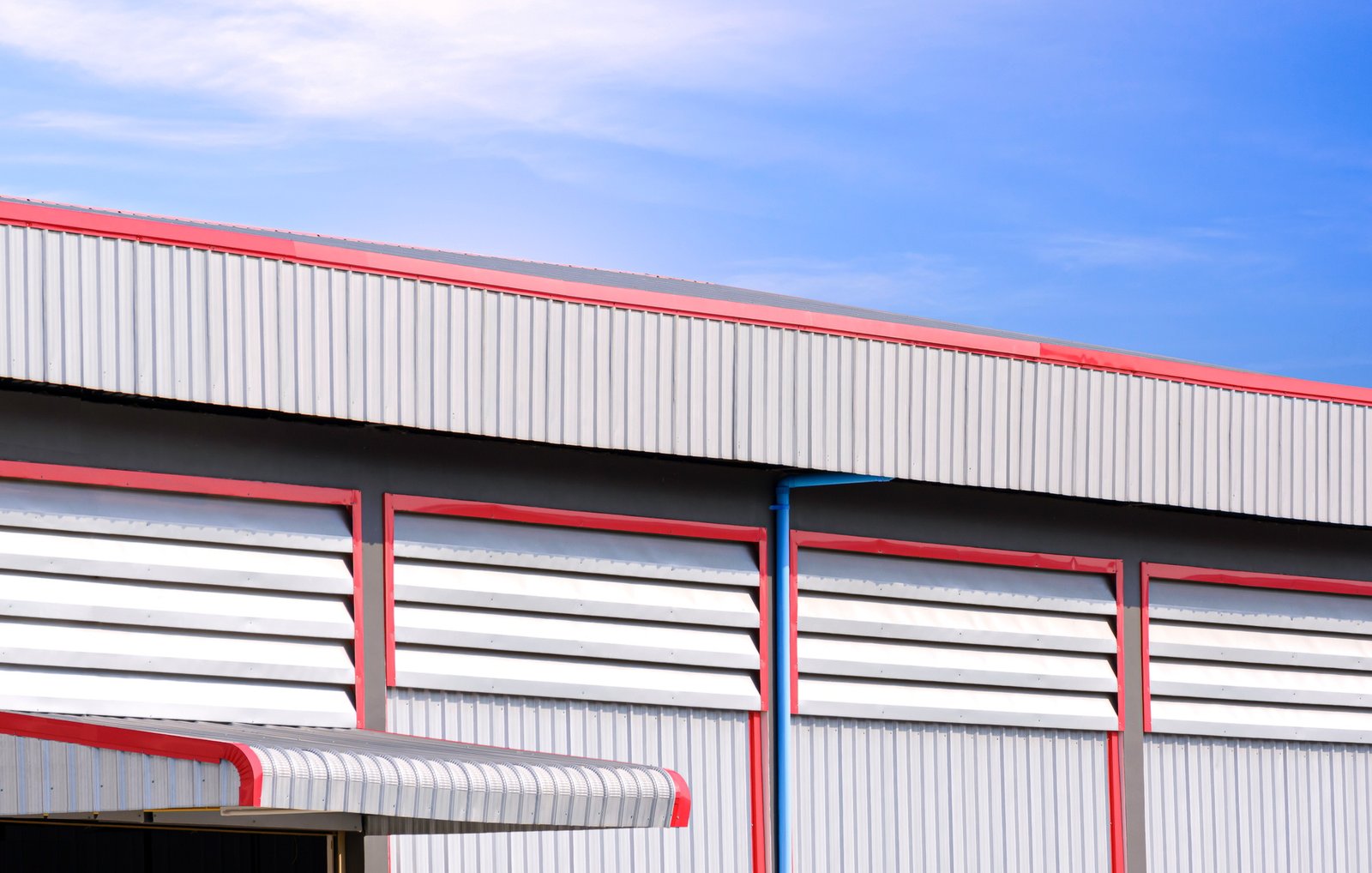 Aluminum Louvers on corrugated steel wall with roof eaves of industrial warehouse building
